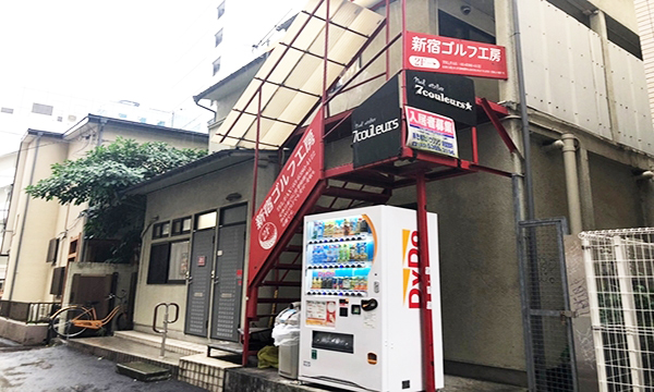 自動販売機があり新宿ゴルフ工房の看板のある建物の2階真ん中になります